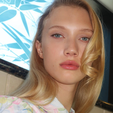 Close-up of a person with blonde hair and floral clothing, with a blurred background